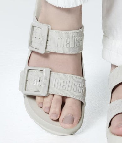 Chinelo adulto Melissa Cozy Slide M.Lover na cor bege claro, com duas tiras largas ajustáveis com fivelas e logo em relevo. Fabricado em Melflex, com solado tratorado e palmilha anatômica. Ideal para quem busca conforto, praticidade e estilo clean no dia a dia.

Palavra-chave principal: Melissa Cozy Slide M.Lover
Palavras-chave relacionadas: chinelo bege claro, slide adulto, tiras com fivela, Melflex, calçado confortável, solado tratorado, estilo minimalista.