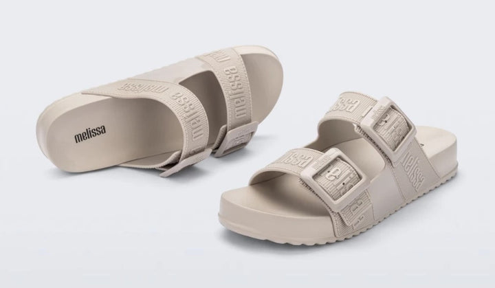 Chinelo adulto Melissa Cozy Slide M.Lover na cor bege claro, com duas tiras largas ajustáveis com fivelas e logo em relevo. Fabricado em Melflex, com solado tratorado e palmilha anatômica. Ideal para quem busca conforto, praticidade e estilo clean no dia a dia.

Palavra-chave principal: Melissa Cozy Slide M.Lover
Palavras-chave relacionadas: chinelo bege claro, slide adulto, tiras com fivela, Melflex, calçado confortável, solado tratorado, estilo minimalista.