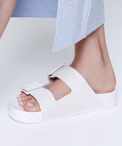 Chinelo adulto Melissa Cozy Slide M.Lover na cor branca, com duas tiras largas ajustáveis com fivelas e logo em relevo. Produzido em Melflex, com solado tratorado e palmilha anatômica. Ideal para looks casuais com conforto, leveza e estilo clean.

Palavra-chave principal: Melissa Cozy Slide M.Lover
Palavras-chave relacionadas: chinelo branco, slide feminino, Melflex, tiras com fivela, solado tratorado, calçado casual, estilo minimalista.