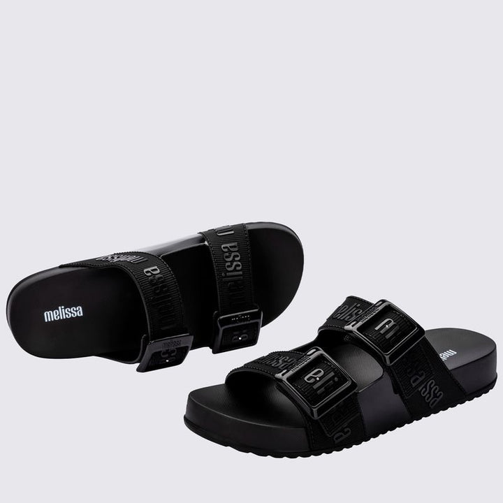 Chinelo adulto Melissa Cozy Slide M.Lover na cor preta, com duas tiras largas ajustáveis com fivelas e logo em relevo. Produzido em Melflex, conta com solado tratorado e palmilha anatômica. Perfeito para compor looks casuais com conforto, praticidade e estilo urbano.

Palavra-chave principal: Melissa Cozy Slide M.Lover
Palavras-chave relacionadas: chinelo preto, slide adulto, tiras com fivela, Melflex, palmilha anatômica, calçado casual, solado tratorado.