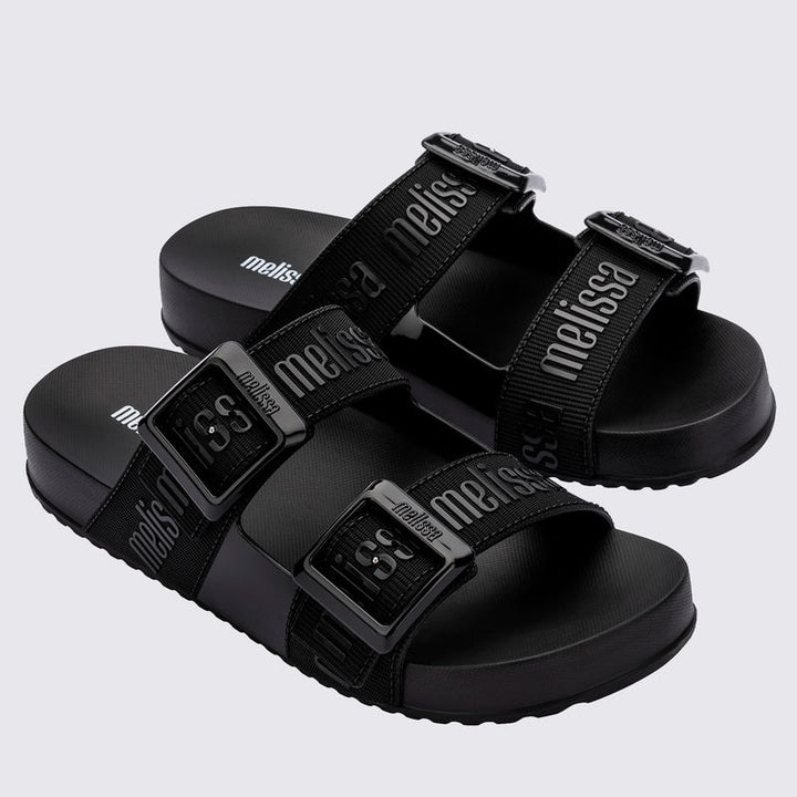 Chinelo adulto Melissa Cozy Slide M.Lover na cor preta, com duas tiras largas ajustáveis com fivelas e logo em relevo. Produzido em Melflex, conta com solado tratorado e palmilha anatômica. Perfeito para compor looks casuais com conforto, praticidade e estilo urbano.

Palavra-chave principal: Melissa Cozy Slide M.Lover
Palavras-chave relacionadas: chinelo preto, slide adulto, tiras com fivela, Melflex, palmilha anatômica, calçado casual, solado tratorado.