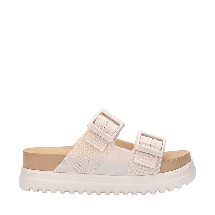 Sandália plataforma Melissa Cozy M.Lover na cor bege, com duas tiras largas ajustáveis com fivelas e logo em relevo. Confeccionada em Melflex, possui solado tratorado e palmilha anatômica, unindo conforto e estilo em um design moderno para looks casuais."