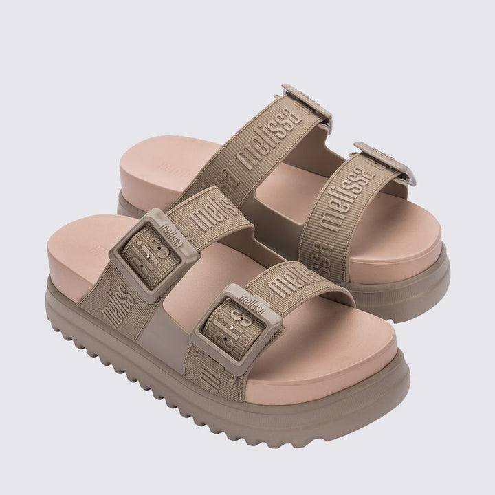 Sandália plataforma Melissa Cozy M.Lover na cor bege médio, com duas tiras largas ajustáveis com fivelas e logo Melissa em relevo. Produzida em Melflex, possui solado alto tratorado e palmilha anatômica, unindo conforto, estilo e praticidade em um visual moderno