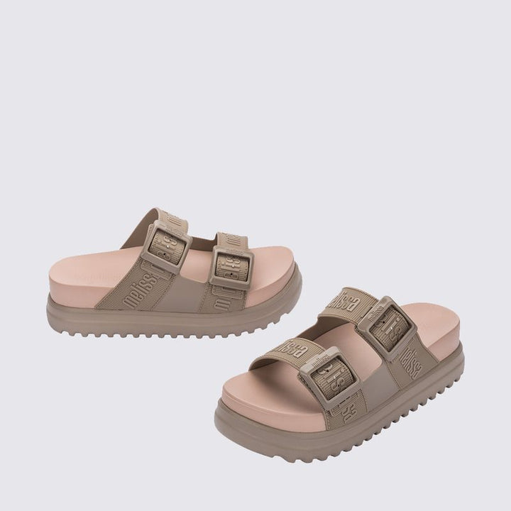 Sandália plataforma Melissa Cozy M.Lover na cor bege médio, com duas tiras largas ajustáveis com fivelas e logo Melissa em relevo. Produzida em Melflex, possui solado alto tratorado e palmilha anatômica, unindo conforto, estilo e praticidade em um visual moderno