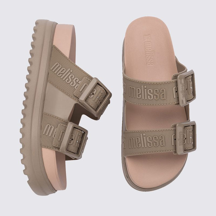 Sandália plataforma Melissa Cozy M.Lover na cor bege médio, com duas tiras largas ajustáveis com fivelas e logo Melissa em relevo. Produzida em Melflex, possui solado alto tratorado e palmilha anatômica, unindo conforto, estilo e praticidade em um visual moderno