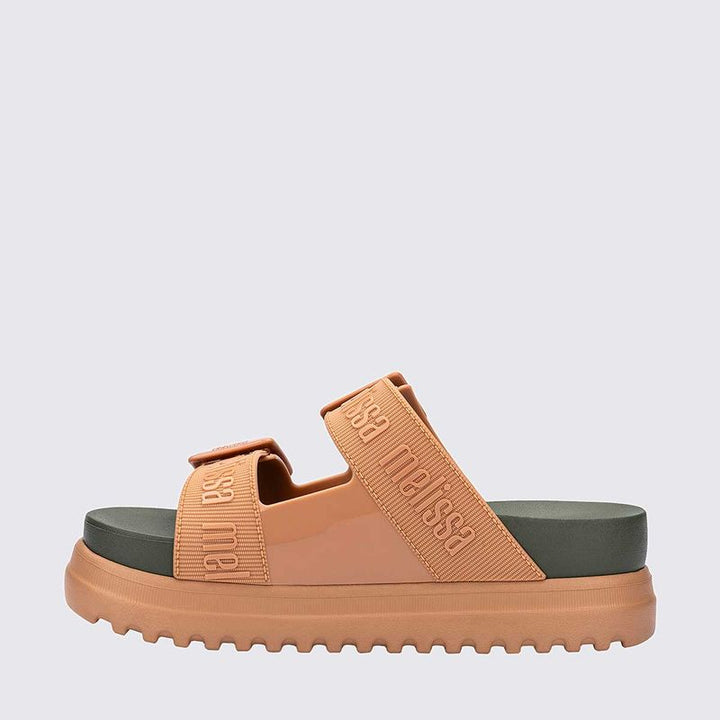 Sandália plataforma adulta Melissa Cozy M.Lover nas cores bege e verde, com duas tiras largas ajustáveis com fivelas e logo em relevo. Confeccionada em Melflex, possui solado tratorado e palmilha anatômica. Ideal para quem busca estilo, conforto e um visual moderno e ousado