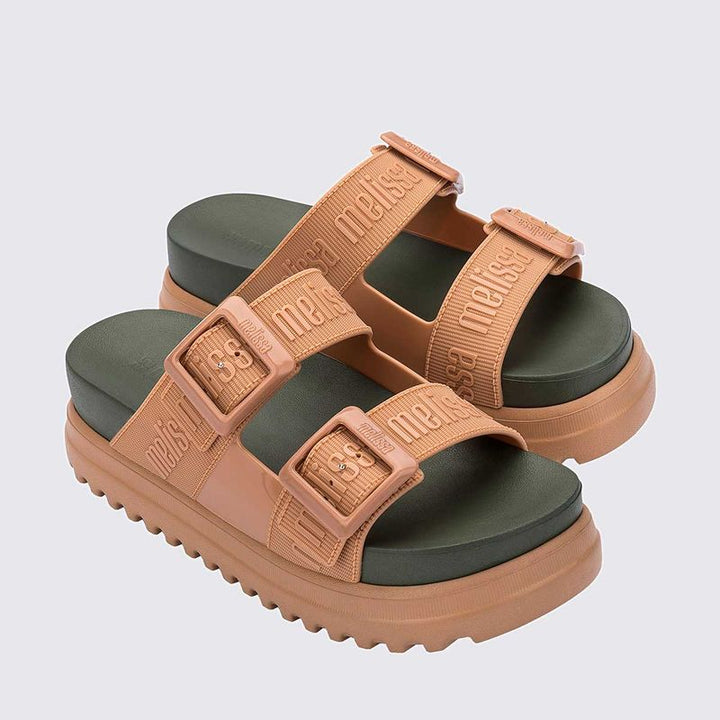 Sandália plataforma adulta Melissa Cozy M.Lover nas cores bege e verde, com duas tiras largas ajustáveis com fivelas e logo em relevo. Confeccionada em Melflex, possui solado tratorado e palmilha anatômica. Ideal para quem busca estilo, conforto e um visual moderno e ousado