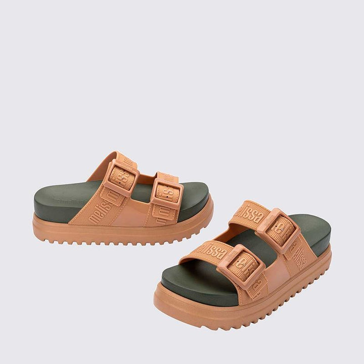 Sandália plataforma adulta Melissa Cozy M.Lover nas cores bege e verde, com duas tiras largas ajustáveis com fivelas e logo em relevo. Confeccionada em Melflex, possui solado tratorado e palmilha anatômica. Ideal para quem busca estilo, conforto e um visual moderno e ousado
