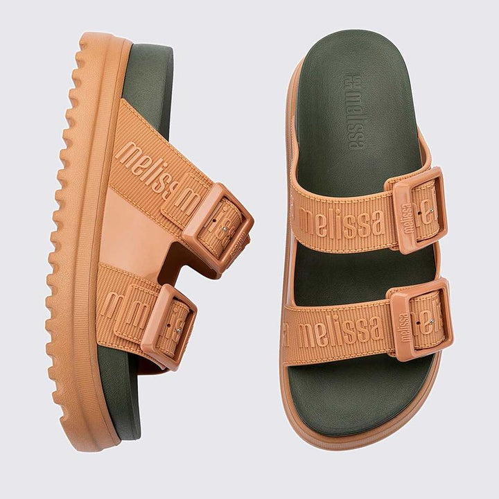Sandália plataforma adulta Melissa Cozy M.Lover nas cores bege e verde, com duas tiras largas ajustáveis com fivelas e logo em relevo. Confeccionada em Melflex, possui solado tratorado e palmilha anatômica. Ideal para quem busca estilo, conforto e um visual moderno e ousado