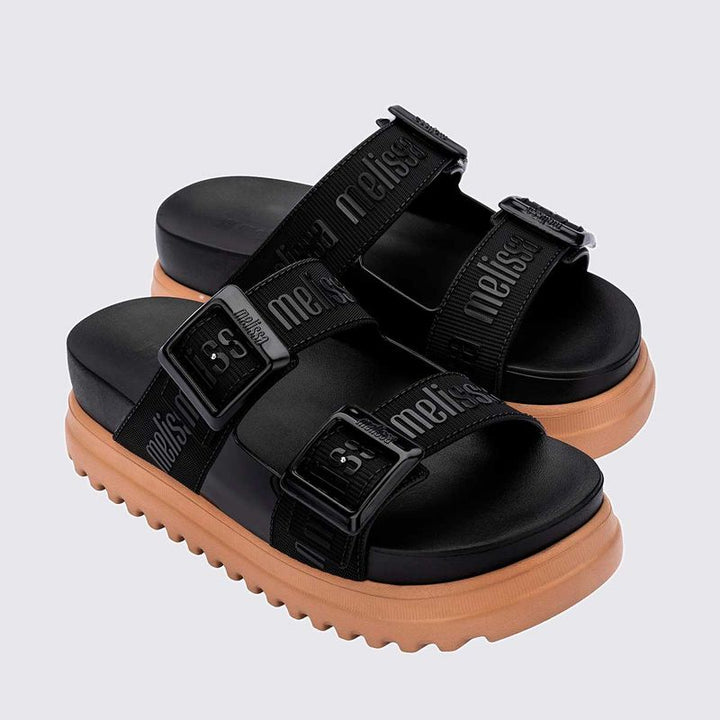 Sandália plataforma Melissa Cozy M.Lover na cor preta, com duas tiras largas ajustáveis com fivelas e logo em relevo. Produzida em Melflex, conta com solado tratorado e palmilha anatômica. Ideal para compor looks casuais com conforto, atitude e estilo urbano