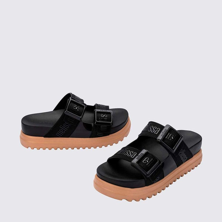 Sandália plataforma Melissa Cozy M.Lover na cor preta, com duas tiras largas ajustáveis com fivelas e logo em relevo. Produzida em Melflex, conta com solado tratorado e palmilha anatômica. Ideal para compor looks casuais com conforto, atitude e estilo urbano