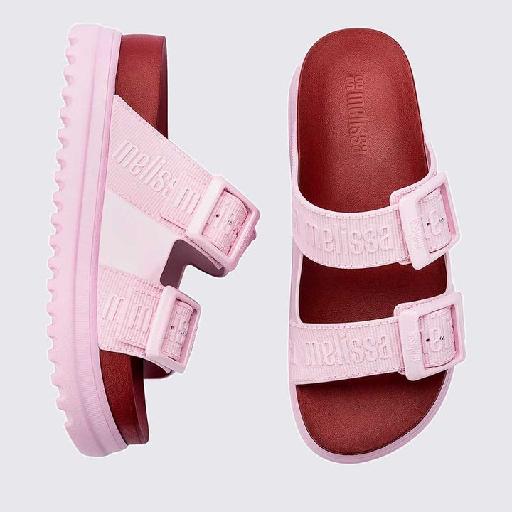 Sandália plataforma adulta Melissa Cozy M.Lover nas cores rosa e vermelho, com duas tiras largas ajustáveis com fivelas e logo em relevo. Produzida em Melflex, com solado tratorado alto e palmilha anatômica, combina conforto, estilo marcante e atitude nos looks casuais