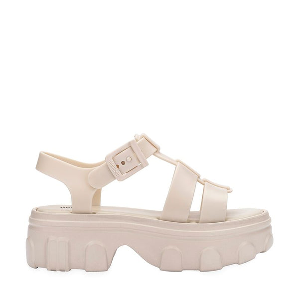 Sandália adulta Melissa Ella na cor bege, com tiras largas, acabamento brilhante e fecho ajustável no tornozelo. Produzida em Melflex, oferece conforto, leveza e estilo para compor looks casuais, versáteis e elegantes