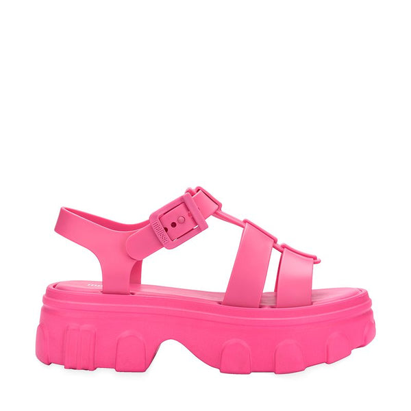 Sandália adulta Melissa Ella na cor rosa, com tiras largas, fecho ajustável no tornozelo e acabamento brilhante. Produzida em Melflex, é leve, confortável e ideal para compor looks casuais e românticos com um toque de estilo moderno