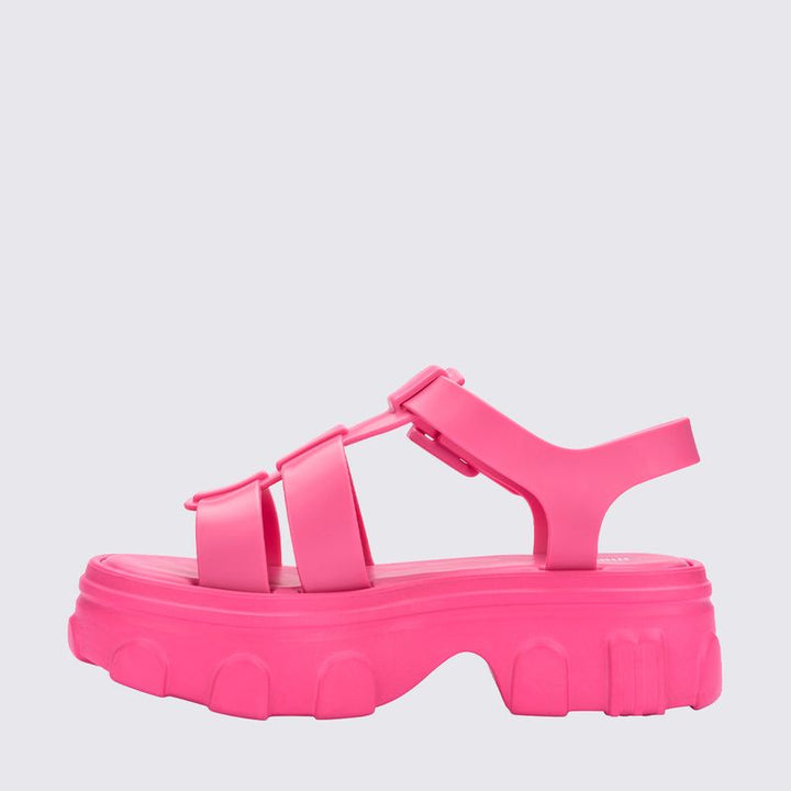 Sandália adulta Melissa Ella na cor rosa, com tiras largas, fecho ajustável no tornozelo e acabamento brilhante. Produzida em Melflex, é leve, confortável e ideal para compor looks casuais e românticos com um toque de estilo moderno