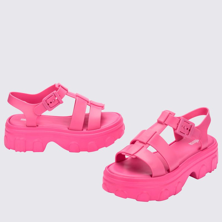 Sandália adulta Melissa Ella na cor rosa, com tiras largas, fecho ajustável no tornozelo e acabamento brilhante. Produzida em Melflex, é leve, confortável e ideal para compor looks casuais e românticos com um toque de estilo moderno