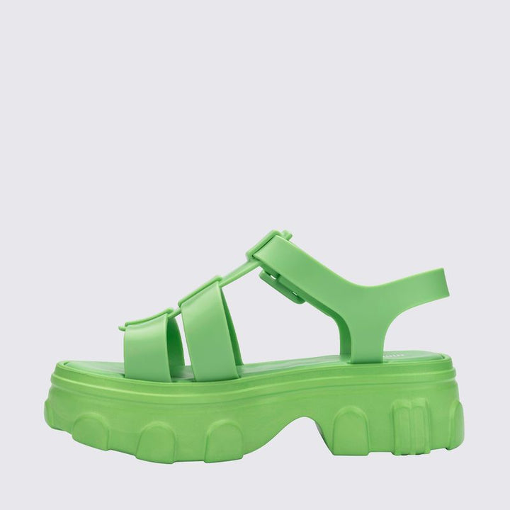 Sandália adulta Melissa Ella na cor verde, com tiras largas e design moderno. Produzida em Melflex, possui solado baixo, acabamento brilhante e fecho ajustável no tornozelo. Ideal para compor looks casuais com conforto e estilo
