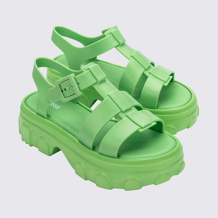 Sandália adulta Melissa Ella na cor verde, com tiras largas e design moderno. Produzida em Melflex, possui solado baixo, acabamento brilhante e fecho ajustável no tornozelo. Ideal para compor looks casuais com conforto e estilo