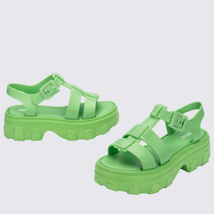 Sandália adulta Melissa Ella na cor verde, com tiras largas e design moderno. Produzida em Melflex, possui solado baixo, acabamento brilhante e fecho ajustável no tornozelo. Ideal para compor looks casuais com conforto e estilo