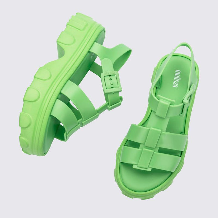 Sandália adulta Melissa Ella na cor verde, com tiras largas e design moderno. Produzida em Melflex, possui solado baixo, acabamento brilhante e fecho ajustável no tornozelo. Ideal para compor looks casuais com conforto e estilo