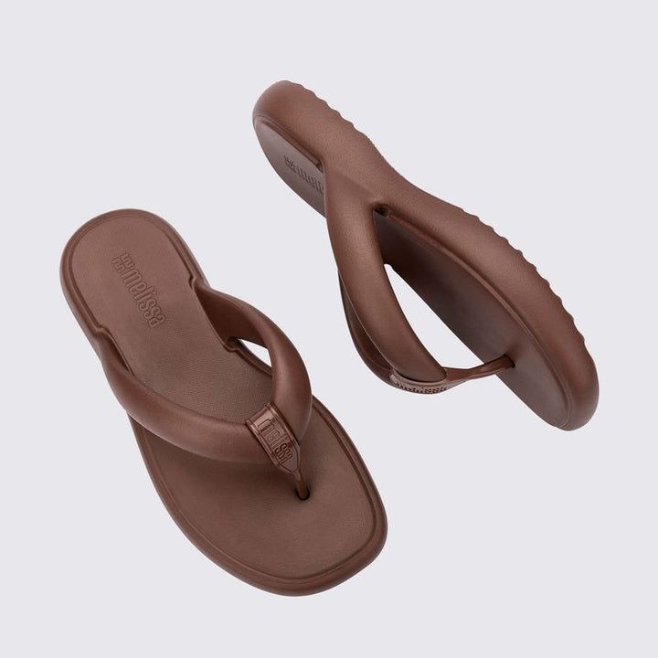 Chinelo adulto Melissa Free Low na cor bronze, com design minimalista, tiras grossas estilo flip-flop e solado anatômico. Confeccionado em Melflex, oferece leveza, conforto e praticidade para o dia a dia com muito estilo.

Palavra-chave principal: Melissa Free Low Chinelo Adulto
Palavras-chave relacionadas: chinelo bronze Melissa, flip-flop feminino, Melflex, chinelo confortável, solado anatômico, calçado casual.