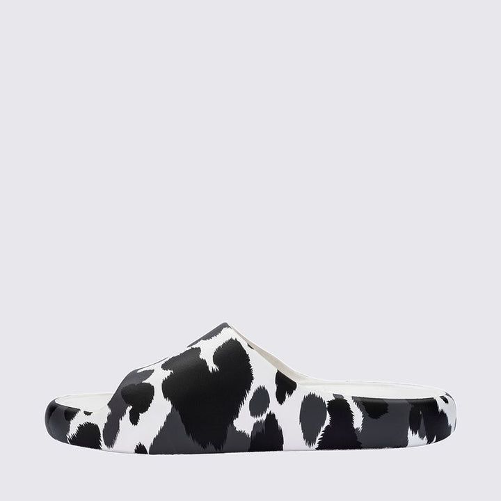 Chinelo adulto Melissa Free Print Slide com uma tira larga estampada nas cores branco e preto. Produzido em Melflex, com solado reto e palmilha confortável. Ideal para looks casuais cheios de estilo e praticidade no dia a dia