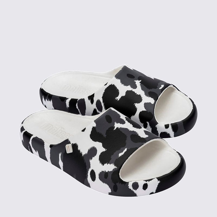 Chinelo adulto Melissa Free Print Slide com uma tira larga estampada nas cores branco e preto. Produzido em Melflex, com solado reto e palmilha confortável. Ideal para looks casuais cheios de estilo e praticidade no dia a dia