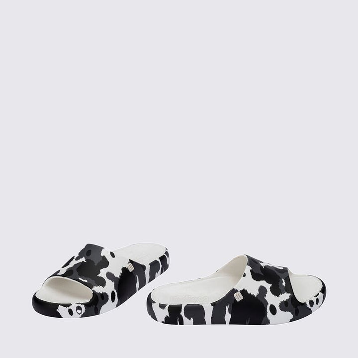 Chinelo adulto Melissa Free Print Slide com uma tira larga estampada nas cores branco e preto. Produzido em Melflex, com solado reto e palmilha confortável. Ideal para looks casuais cheios de estilo e praticidade no dia a dia