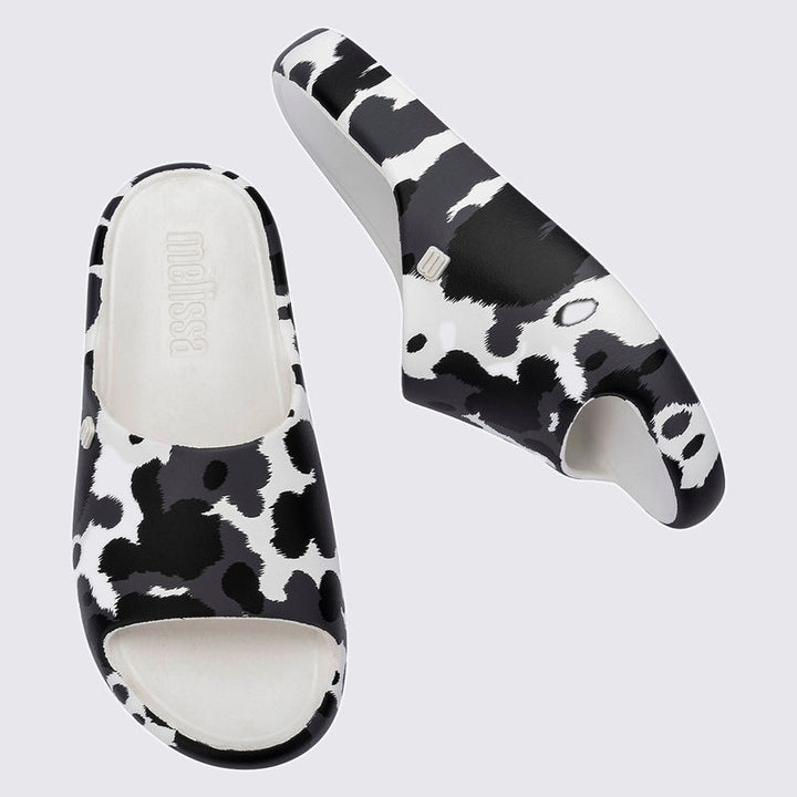 Chinelo adulto Melissa Free Print Slide com uma tira larga estampada nas cores branco e preto. Produzido em Melflex, com solado reto e palmilha confortável. Ideal para looks casuais cheios de estilo e praticidade no dia a dia
