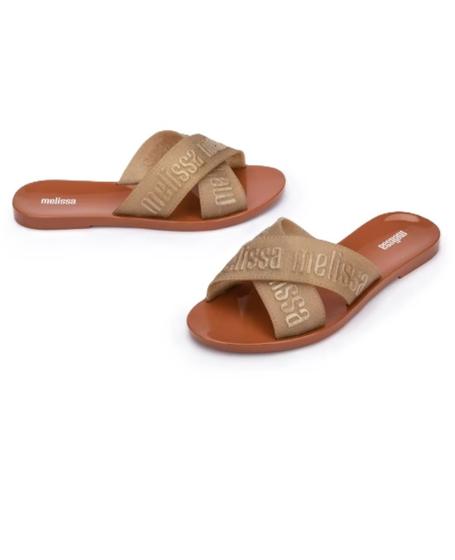 Sandália Melissa M Lover Slide adulto nas cores marrom e ouro, com tira larga texturizada, solado reto e design minimalista – calçado moderno, confortável e ideal para o dia a dia.

Palavra-chave principal:
Melissa M Lover Slide

Palavras-chave relacionadas:
Melissa 35740, slide marrom ouro Melissa, sandália bicolor Melissa, calçado confortável adulto, Melissa com tira larga, sandália minimalista, slide casual, sandália estilosa feminina, Melissa moderna, sandália leve adulto