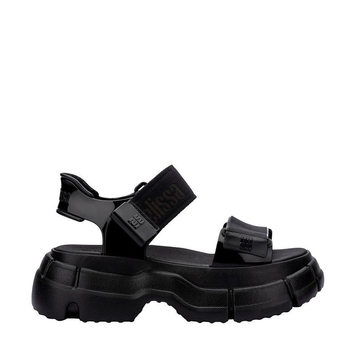 Sandália Melissa Pulse na cor preta, com tiras largas e fechamento ajustável no tornozelo. Produzida em Melflex, possui solado robusto que garante conforto e estilo. Ideal para compor looks urbanos, modernos e versáteis no dia a dia