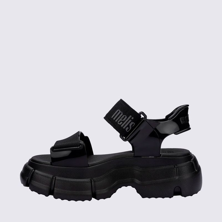 Sandália Melissa Pulse na cor preta, com tiras largas e fechamento ajustável no tornozelo. Produzida em Melflex, possui solado robusto que garante conforto e estilo. Ideal para compor looks urbanos, modernos e versáteis no dia a dia