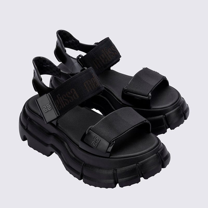 Sandália Melissa Pulse na cor preta, com tiras largas e fechamento ajustável no tornozelo. Produzida em Melflex, possui solado robusto que garante conforto e estilo. Ideal para compor looks urbanos, modernos e versáteis no dia a dia