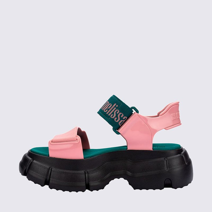 Sandália Melissa Pulse nas cores preto e rosa, com tiras largas e fechamento ajustável no tornozelo. Confeccionada em Melflex, possui solado robusto e confortável. Perfeita para looks urbanos e estilosos, unindo praticidade, personalidade e design moderno