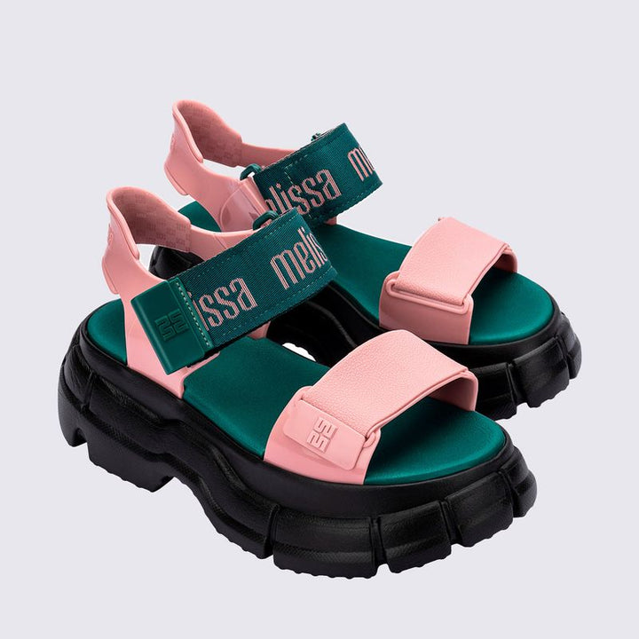 Sandália Melissa Pulse nas cores preto e rosa, com tiras largas e fechamento ajustável no tornozelo. Confeccionada em Melflex, possui solado robusto e confortável. Perfeita para looks urbanos e estilosos, unindo praticidade, personalidade e design moderno