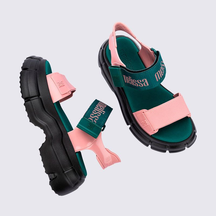 Sandália Melissa Pulse nas cores preto e rosa, com tiras largas e fechamento ajustável no tornozelo. Confeccionada em Melflex, possui solado robusto e confortável. Perfeita para looks urbanos e estilosos, unindo praticidade, personalidade e design moderno