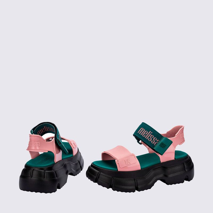 Sandália Melissa Pulse nas cores preto e rosa, com tiras largas e fechamento ajustável no tornozelo. Confeccionada em Melflex, possui solado robusto e confortável. Perfeita para looks urbanos e estilosos, unindo praticidade, personalidade e design moderno