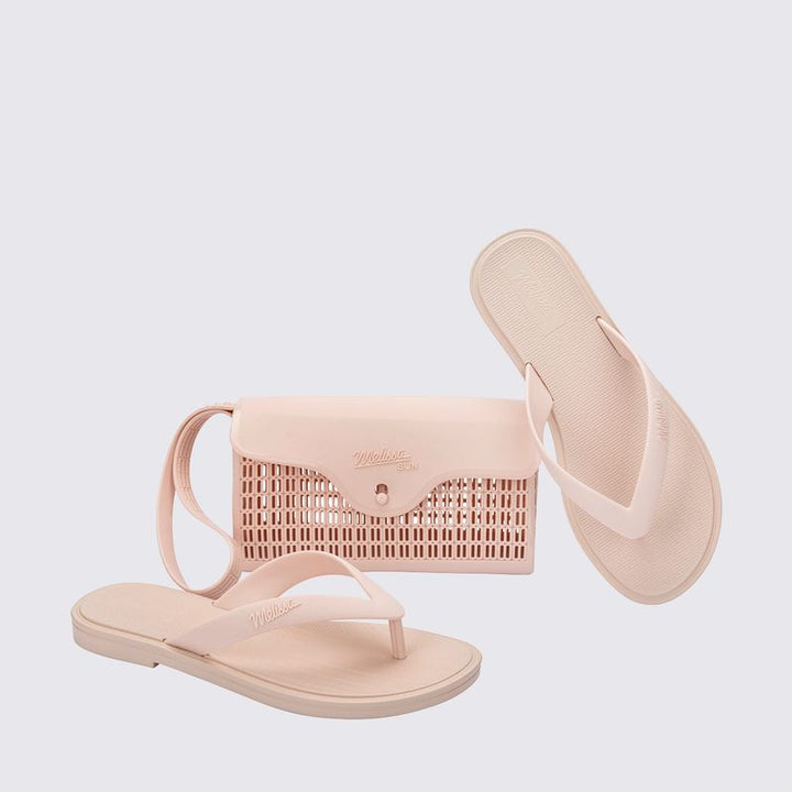 chinelo, com acabamento fosco e feito em Melflex, é superconfortável, resistente e ideal para o dia a dia — desde um passeio no parque até aquele almoço de domingo em família. Já a bolsa bege que acompanha é um show à parte: compacta, mas espaçosa, com 1 litro de capacidade, perfeita para carregar os itens essenciais com estilo.