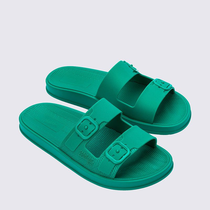 Sandália Melissa Sun Cruise adulto na cor verde com acabamento brilhante e translúcido. Feita em material Melflex, possui design moderno com tiras largas e confortáveis. O solado rasteiro oferece leveza e praticidade, e o fechamento ajustável garante segurança e conforto ao caminhar. Ideal para compor looks casuais, descontraídos e cheios de estilo.