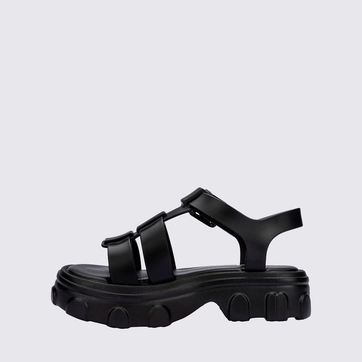 Sandália infantil Mini Melissa Ella na cor preta, com tiras largas, acabamento brilhante e fecho ajustável no tornozelo. Produzida em Melflex, é leve, confortável e ideal para compor looks infantis estilosos e práticos para o dia a dia