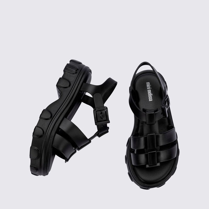 Sandália infantil Mini Melissa Ella na cor preta, com tiras largas, acabamento brilhante e fecho ajustável no tornozelo. Produzida em Melflex, é leve, confortável e ideal para compor looks infantis estilosos e práticos para o dia a dia