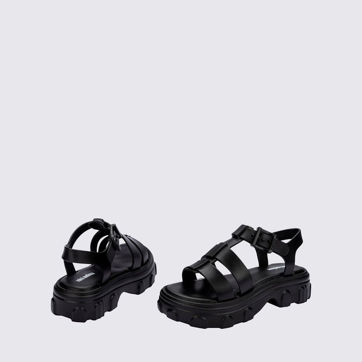 Sandália infantil Mini Melissa Ella na cor preta, com tiras largas, acabamento brilhante e fecho ajustável no tornozelo. Produzida em Melflex, é leve, confortável e ideal para compor looks infantis estilosos e práticos para o dia a dia