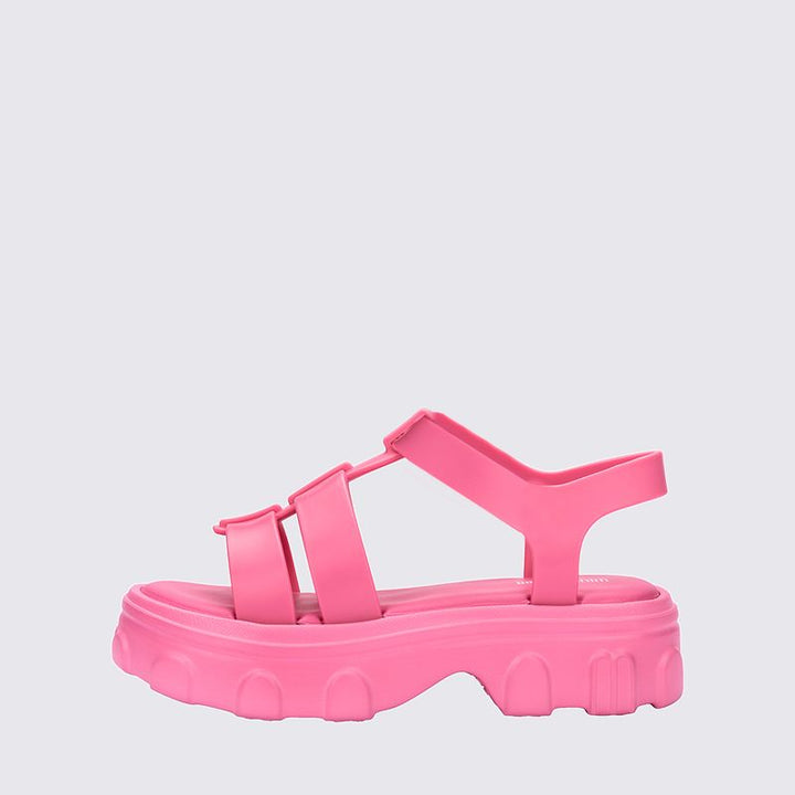 Sandália infantil Mini Melissa Ella na cor rosa, com tiras largas, acabamento brilhante e fecho ajustável no tornozelo. Feita em Melflex, é leve, confortável e ideal para compor looks infantis com estilo, praticidade e um toque delicado