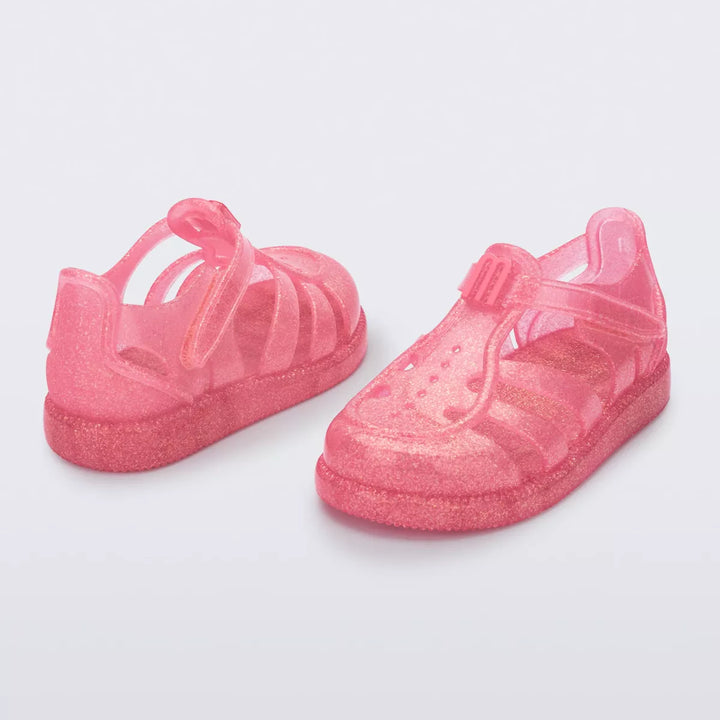 Sandália infantil Mini Melissa Hip Daydream Baby na cor rosa com glitter, design translúcido e tiras vazadas. Possui fechamento em velcro e detalhe frontal com o 'M' da marca. Produzida em Melflex, é leve, confortável e ideal para os primeiros passos com muito brilho e segurança.

Palavra-chave principal: Mini Melissa Hip Daydream Baby
Palavras-chave relacionadas: rosa glitter, sandália baby, Melflex, calçado infantil, primeiros passos, conforto, fechamento em velcro, brilho infantil.