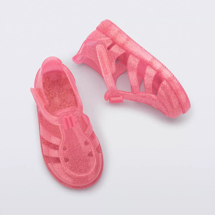 Sandália infantil Mini Melissa Hip Daydream Baby na cor rosa com glitter, design translúcido e tiras vazadas. Possui fechamento em velcro e detalhe frontal com o 'M' da marca. Produzida em Melflex, é leve, confortável e ideal para os primeiros passos com muito brilho e segurança.

Palavra-chave principal: Mini Melissa Hip Daydream Baby
Palavras-chave relacionadas: rosa glitter, sandália baby, Melflex, calçado infantil, primeiros passos, conforto, fechamento em velcro, brilho infantil.