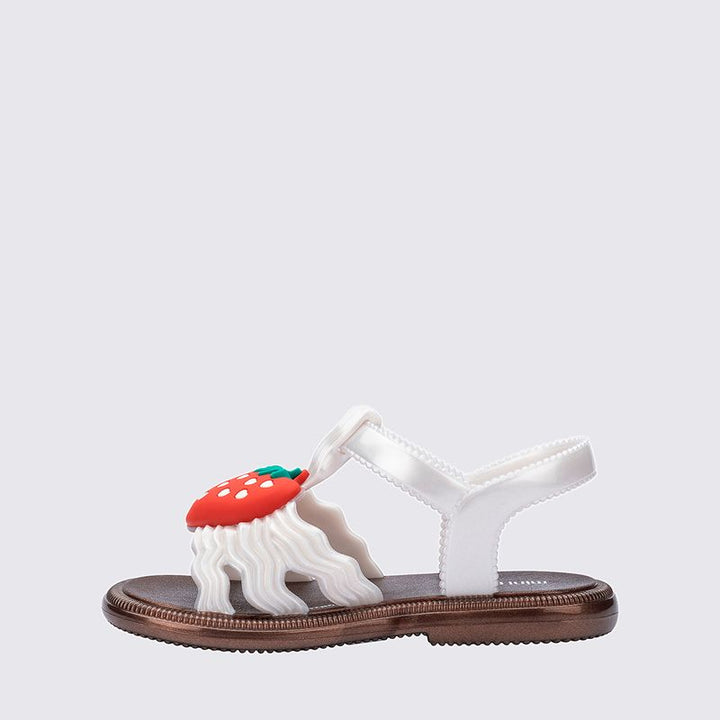 Sandália infantil Mini Melissa Hip Sandal Baby nas cores bronze e branco perolado, com tiras largas e fechamento em velcro. Produzida em Melflex, é leve, confortável e segura, perfeita para os primeiros passos com brilho delicado e muito estilo