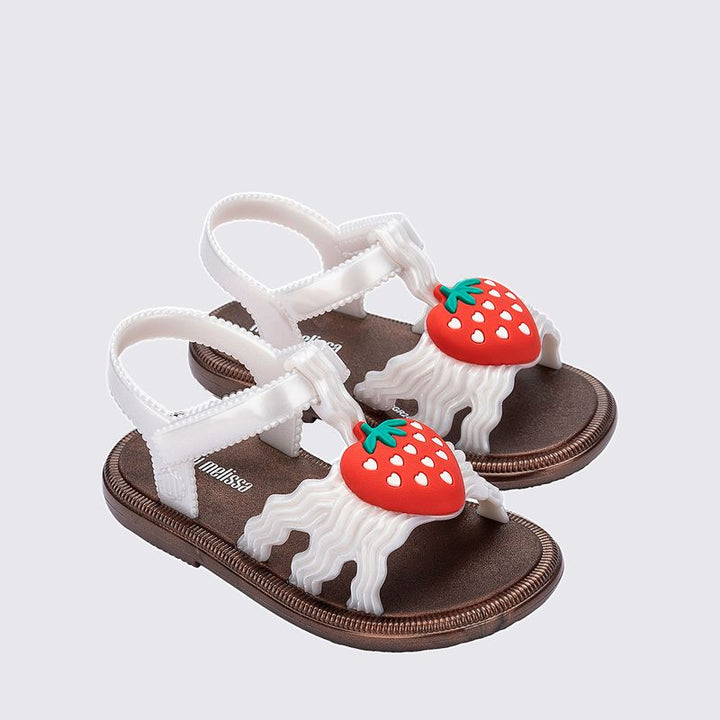 Sandália infantil Mini Melissa Hip Sandal Baby nas cores bronze e branco perolado, com tiras largas e fechamento em velcro. Produzida em Melflex, é leve, confortável e segura, perfeita para os primeiros passos com brilho delicado e muito estilo