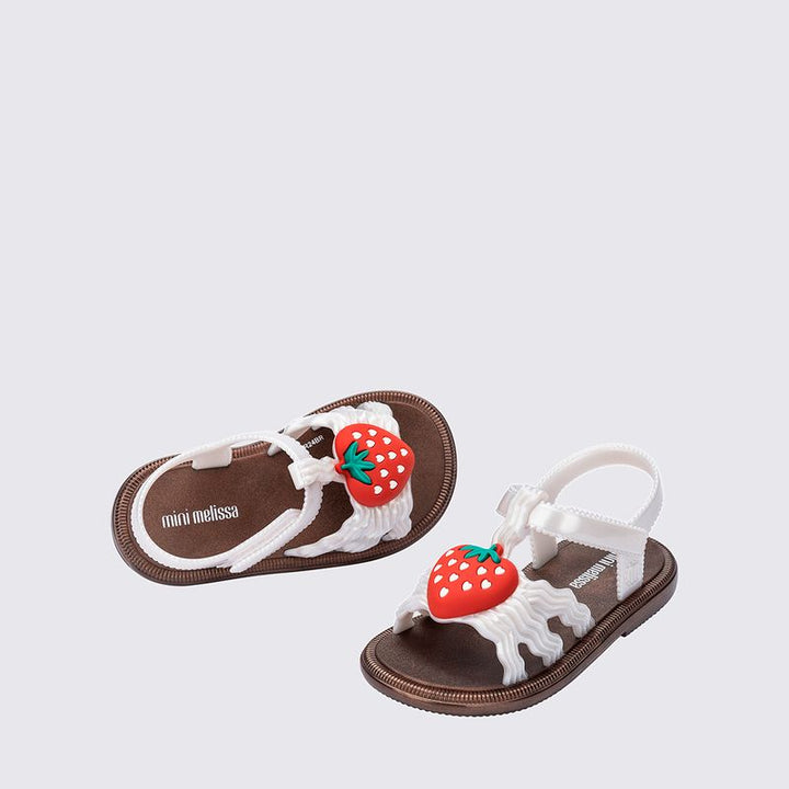 Sandália infantil Mini Melissa Hip Sandal Baby nas cores bronze e branco perolado, com tiras largas e fechamento em velcro. Produzida em Melflex, é leve, confortável e segura, perfeita para os primeiros passos com brilho delicado e muito estilo