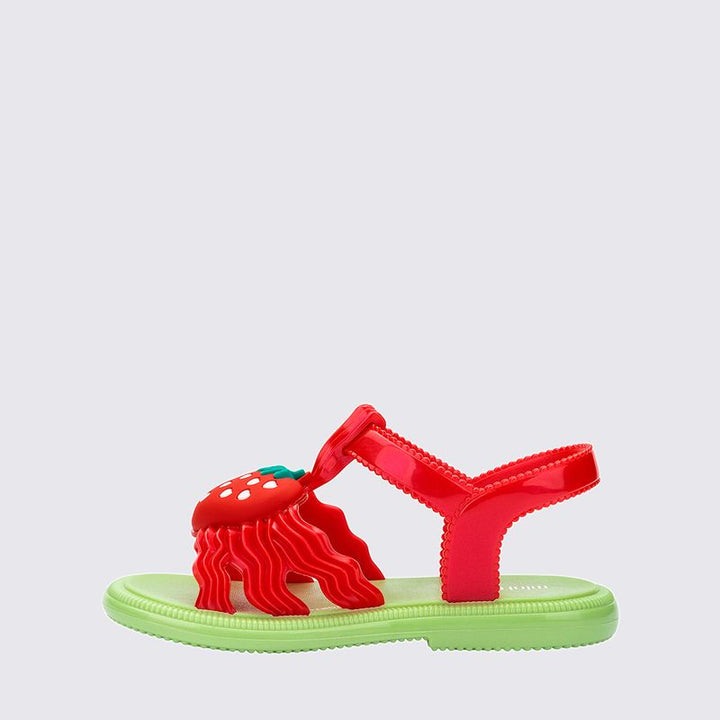Sandália infantil Mini Melissa Hip Sandal Baby nas cores verde e vermelho, com tiras largas e fechamento em velcro. Confeccionada em Melflex, é leve, confortável e segura, ideal para acompanhar os primeiros passos com estilo divertido e prático