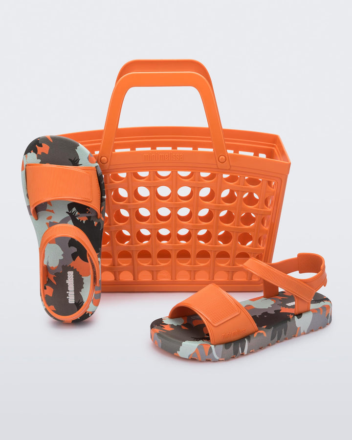 Sandália infantil Mini Melissa Imagine Baby nas cores laranja e verde, com acabamento estampado vibrante e divertido. Feita em material Melflex, macia, leve e confortável, possui fechamento ajustável que garante segurança para os primeiros passos. O conjunto acompanha uma charmosa bolsa de mão combinando nas mesmas cores, com capacidade de 5 litros, perfeita para levar itens essenciais com praticidade e muito estilo no dia a dia.